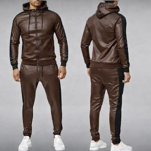 May include: A brown faux leather tracksuit featuring a hooded zip-up jacket and matching pants. The jacket and pants have black stripes down the sides. The tracksuit is a two-piece set.