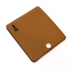 May include: A brown leather wallet with a snap closure and the letter "A" printed on the front.
