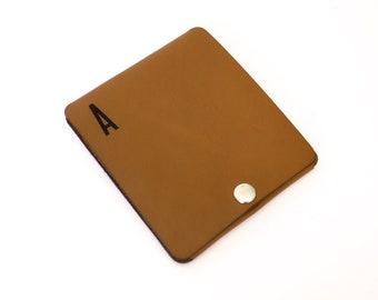 May include: A brown leather wallet with a snap closure and the letter "A" printed on the front.