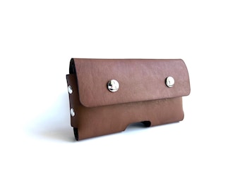 May include: A brown leather phone case with silver snaps. The case has a flap that folds over the top of the phone.