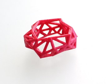 May include: A bright pink, geometric ring made of thin plastic. The ring is a 3D printed design with a lattice pattern.