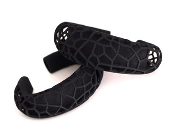 May include: Two black geometric patterned hair bands. The bands are made of a flexible material and have a geometric pattern.