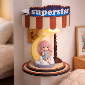 Puede incluir: Estante decorativo con una lámpara con temática de circo y una figura de una niña sentada en una nube junto a una luna creciente. La lámpara tiene una pantalla a rayas rojas y blancas con la palabra "superstar". La figura tiene cabello rosado y un vestido azul.