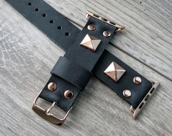 May include: Black leather Apple Watch strap with rose gold accents and pyramid-shaped studs.