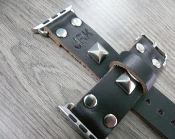 May include: Black leather Apple Watch strap with silver studs and a silver buckle. The strap has the word "JRK" embossed on it.