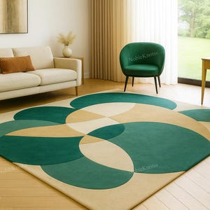 May include: A contemporary rug with a geometric pattern in green, beige, and cream. The rectangular rug features overlapping circular shapes. It's placed on a wooden floor, with a sofa and chairs in the room. The room has a modern design.