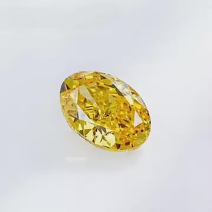 May include: A brilliant, oval-cut yellow diamond. The gemstone is a vibrant, saturated yellow color, with multiple facets that reflect light. The diamond is set against a white background.