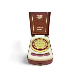 May include: A vintage Zeiss Ikon Ikophot light meter in a brown leather case. The meter has a circular dial with numbers and markings, and the case is embossed with the Zeiss Ikon logo and "Stuttgart Germany".