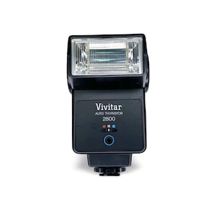以下が含まれることがあります： 黒色のVivitar Auto Thyristor 2800カメラフラッシュ。 フラッシュは、透明で溝のある光拡散器を備えた長方形のヘッドを備えています。 フラッシュの前面には、Vivitarのロゴとモデル番号、インジケーターライト、青いボタンがあります。