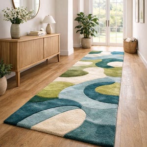May include: A long, abstract patterned rug in shades of blue, green, and cream. The rug features a flowing, organic design with rounded shapes. It is placed on a wooden floor in a hallway setting.