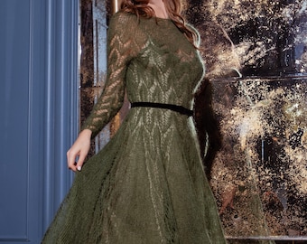 May include: Olive green long-sleeved dress with a black velvet belt. The dress features a round neckline and a flared skirt. The fabric has a delicate, open-knit pattern. The dress is floor-length and appears to be made of a soft, flowing material.