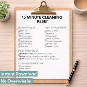 May include: A clipboard with a checklist titled "15 Minute Cleaning Reset" with cleaning tasks. A black and gold pen rests on the wooden surface. A small plant and a cup of coffee are in the background.