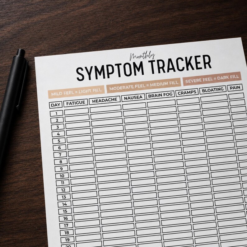 Puede incluir: Una hoja de seguimiento mensual de s&iacute;ntomas con texto y l&iacute;neas de cuadr&iacute;cula en negro sobre papel blanco. El encabezado dice Monthly SYMPTOM TRACKER. Las columnas incluyen fatigue, headache, nausea, brain fog, cramps, bloating y pain. Un bol&iacute;grafo.