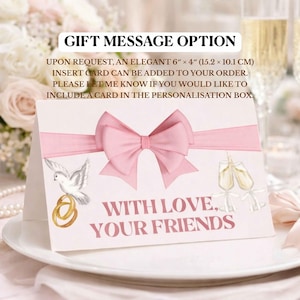 Pode incluir: Cart&atilde;o branco com la&ccedil;o e fita rosa, apresentando uma pomba com alian&ccedil;as e ta&ccedil;as de champanhe. O texto "WITH LOVE, YOUR FRIENDS" &eacute; exibido. O cart&atilde;o mede 15,2 cm x 10,1 cm.