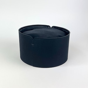 Może przedstawiać: Granatowy, cylindryczny kapelusz z zaokrąglonym wierzchem. Kapelusz ma strukturalne rondo i miękkie, wyściełane wnętrze. Design kapelusza jest prosty i elegancki, odpowiedni na różne okazje.