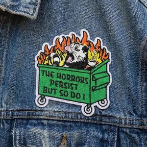 May include: A white ceramic mug with a black handle and the text "But First, Coffee" in a black, handwritten-style font. The mug is on a white surface.