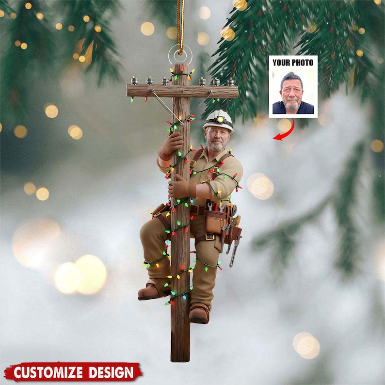 Puede incluir: Adorno navide&ntilde;o que representa a un trabajador de la electricidad subiendo a un poste de madera adornado con luces de colores. El adorno incluye un &aacute;rea para fotos y el texto "CUSTOMIZE DESIGN". El trabajador lleva casco, guantes y cintur&oacute;n de herramientas.