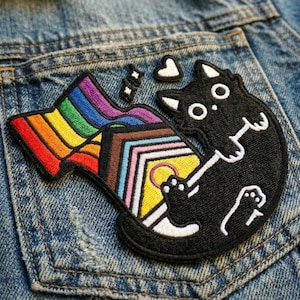 May include: A white ceramic mug with a black handle and the text "But First, Coffee" in a bold, black font. The mug is set against a blurred background, suggesting a cozy setting.