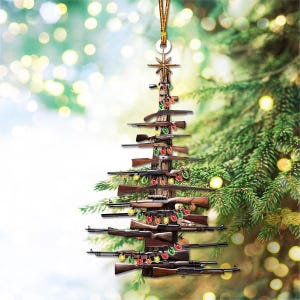 K&ouml;nnte beinhalten: Weihnachtsbaumschmuck in Form eines Baumes, der aus verschiedenen Gewehren besteht. Der Baum ist mit bunten Lichterketten geschm&uuml;ckt und mit einem goldenen Stern gekr&ouml;nt. Der Schmuck h&auml;ngt an einer goldenen Schnur.