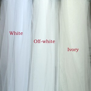 Peut inclure: Gros plan sur trois &eacute;chantillons de tissu transparent &eacute;tiquet&eacute;s "Blanc", "Blanc cass&eacute;" et "Ivoire". Les tissus sont drap&eacute;s, mettant en valeur leurs diff&eacute;rentes nuances de blanc et de blanc cass&eacute;. Le texte est en rouge.