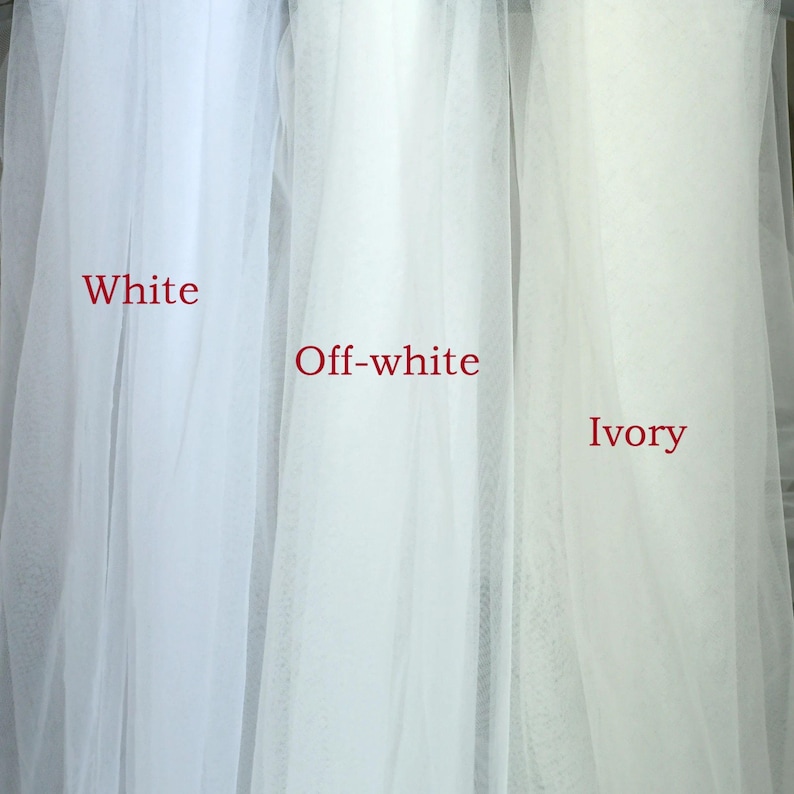 Peut inclure: Gros plan sur trois &eacute;chantillons de tissu transparent &eacute;tiquet&eacute;s "Blanc", "Blanc cass&eacute;" et "Ivoire". Les tissus sont drap&eacute;s, mettant en valeur leurs diff&eacute;rentes nuances de blanc et de blanc cass&eacute;. Le texte est en rouge.