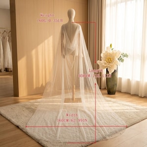 Peut inclure: Une cape de mari&eacute;e ivoire transparente, orn&eacute;e de perles, pr&eacute;sent&eacute;e sur un mannequin. La cape mesure 300 cm de long et 160 cm de large. Son poids est de 160g. Le design est fluide et l&eacute;ger, id&eacute;al pour une robe de mari&eacute;e.