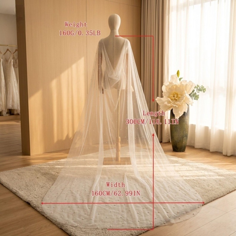 Peut inclure: Une cape de mari&eacute;e ivoire transparente, orn&eacute;e de perles, pr&eacute;sent&eacute;e sur un mannequin. La cape mesure 300 cm de long et 160 cm de large. Son poids est de 160g. Le design est fluide et l&eacute;ger, id&eacute;al pour une robe de mari&eacute;e.
