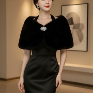 May include: A black faux fur shawl with a decorative rhinestone clasp. The shawl is worn over a black halter dress. The image is a medium shot, showcasing the elegant design and texture of the formal wear.