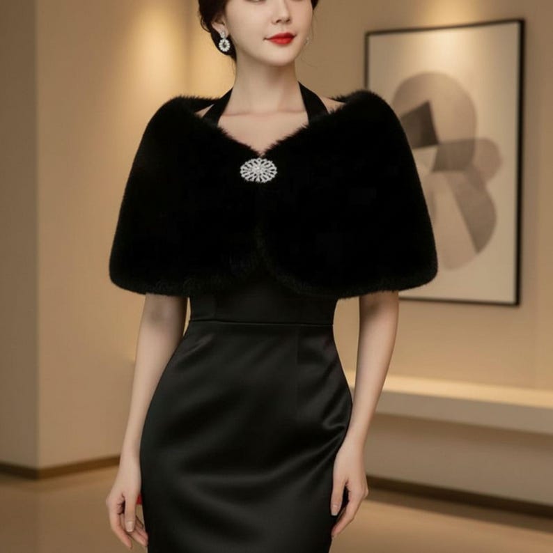 May include: A black faux fur shawl with a decorative rhinestone clasp. The shawl is worn over a black halter dress. The image is a medium shot, showcasing the elegant design and texture of the formal wear.