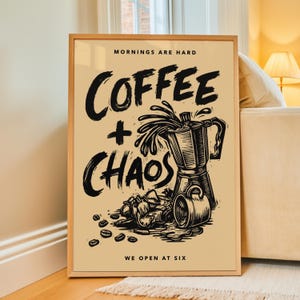 May include: A rectangular framed wall art print on a light tan background featuring black ink-style illustrations of a moka pot, a coffee cup, and scattered coffee beans. The text reads MORNINGS ARE HARD, COFFEE + CHAOS, and WE OPEN AT SIX.