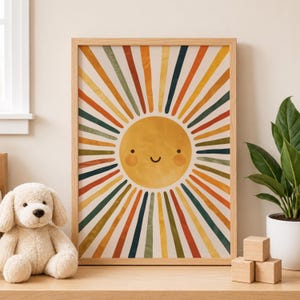 Op de afbeelding: Een ingelijste kunstprint met een lachende zon met kleurrijke stralen in oranje, geel, groen en blauw. Het kunstwerk heeft een retro-stijl en wordt getoond op een houten oppervlak. Een pluchen hondenspeelgoed en een potplant zijn ook zichtbaar.