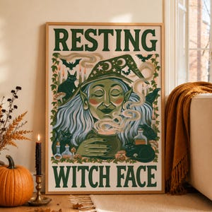 May include: A framed wall art print featuring a green-skinned witch with long hair and a pointed hat, holding a steaming mug. The text RESTING WITCH FACE is printed in dark green. The illustration includes black cats, bats, candles, and mushrooms.