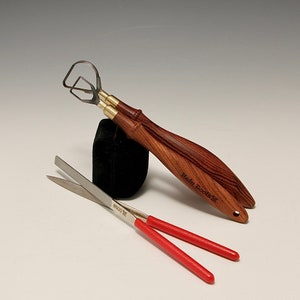 Peut inclure: Ensemble d'outils de poterie comprenant deux outils à boucle avec manches en bois et une paire de ciseaux à poignées rouges. Les outils à boucle ont des viroles en laiton et sont marqués "Hein Tools". Les ciseaux sont marqués "#600".