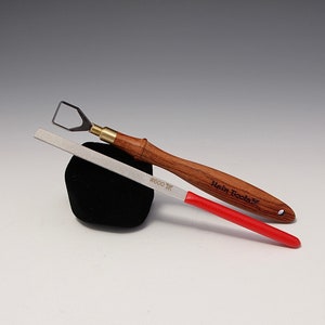 Può includere: Un set di due strumenti per intagliare il legno. Un coltello da intaglio con manico in legno e una virola in ottone e una lima in metallo con manico rosso. La lima è etichettata #600.