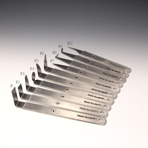 May include: A set of ten silver-toned metal tools with numbered handles. The tools are labeled #1 through #10 and are labeled "Hain Goola" with the corresponding number.