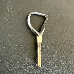 May include: A silver metal key with a unique triangular shaped head and a threaded shaft.