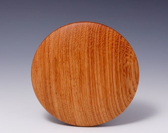 May include: A round wooden coaster with a natural wood grain finish. The coaster is made of light brown wood with a smooth surface.