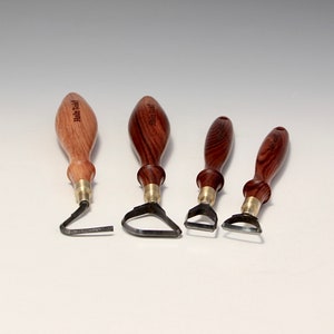 Può includere: Quattro strumenti per intagliare il legno con lame di forme diverse. Gli strumenti hanno manici in legno con venature scure e dettagli in ottone. Le lame sono in metallo e hanno un bordo affilato.