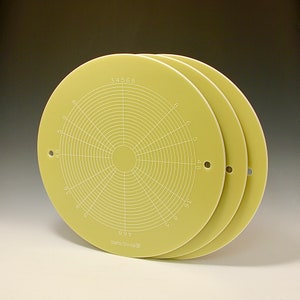 Peut inclure: Trois outils circulaires vert pâle avec des cercles concentriques et des lignes radiales, avec des chiffres et le texte "Beta Scale III". Chaque outil a un petit trou près du bord. Les outils sont légèrement empilés, révélant leur conception.