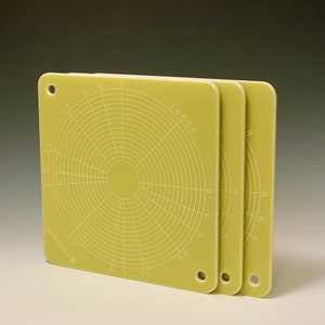 May include: Three yellow plastic circular rulers with concentric circles and numbered markings. The rulers are stacked on top of each other.