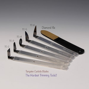 May include: Set of six tungsten carbide blades with a diamond file. The blades are labeled TC-2, TC-3, TC-4, TC-5, and TC-6. The text "Tungsten Carbide Blades The Hardest Trimming Tools!!" is printed below the blades.
