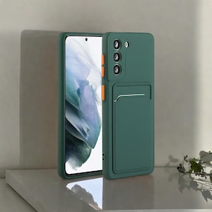 以下が含まれることがあります： カードホルダーとオレンジ色のアクセントが付いた、ティール色のスマートフォンケース。スマートフォンの画面には風景画像が表示されています。このケースは、スマートフォンを保護し、便利な収納ソリューションを提供するように設計されています。