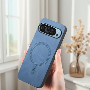 Könnte beinhalten: Eine blaue Handyhülle mit schwarzem Rand. Die Hülle hat ein kreisförmiges Design mit einer vertikalen Linie darunter und einen Kameraausschnitt. Die Hülle wird in der Hand einer Person gehalten.