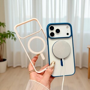 Puede incluir: Una funda transparente para tel&eacute;fono con un marco rosa claro y un dise&ntilde;o de c&iacute;rculo blanco. Una funda de tel&eacute;fono blanca y azul con un c&iacute;rculo plateado y un cable blanco. La funda tiene un borde azul.
