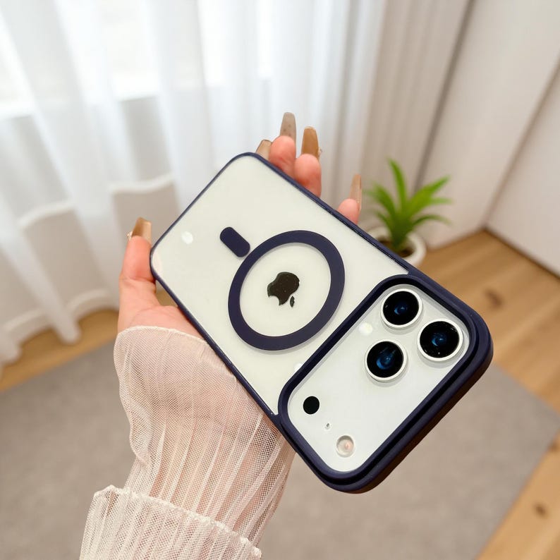 Puede incluir: Una funda transparente para tel&eacute;fono con un borde azul marino y un dise&ntilde;o de c&iacute;rculo azul marino. La funda tiene un interior blanco con un logotipo de manzana negro. La funda tiene tres lentes de c&aacute;mara y un peque&ntilde;o punto en la parte inferior.