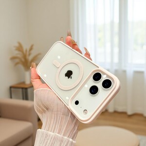 Puede incluir: Una funda transparente para tel&eacute;fono con borde y detalles en rosa claro. La funda tiene un acento rosa circular alrededor del logotipo del tel&eacute;fono y una secci&oacute;n rectangular para las lentes de la c&aacute;mara. La funda est&aacute; decorada con peque&ntilde;os puntos blancos.