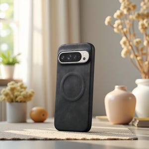 May include: A black phone case with a camera module and a circular design on the back. The case is made of a textured material and is standing upright on a table. The background includes a window, flowers, and decorative vases.