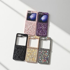 May include: Six open flip phone cases in various colours, including pink, purple, black, gold, and grey. The cases are decorated with sparkling embellishments. The phone screens display the time 21:24.