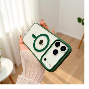 Puede incluir: Una funda transparente para tel&eacute;fono con borde y detalles verdes. La funda presenta un c&iacute;rculo verde con el logotipo de una manzana negra y un recorte para la c&aacute;mara. La funda est&aacute; dise&ntilde;ada para proteger el tel&eacute;fono de ara&ntilde;azos y da&ntilde;os.