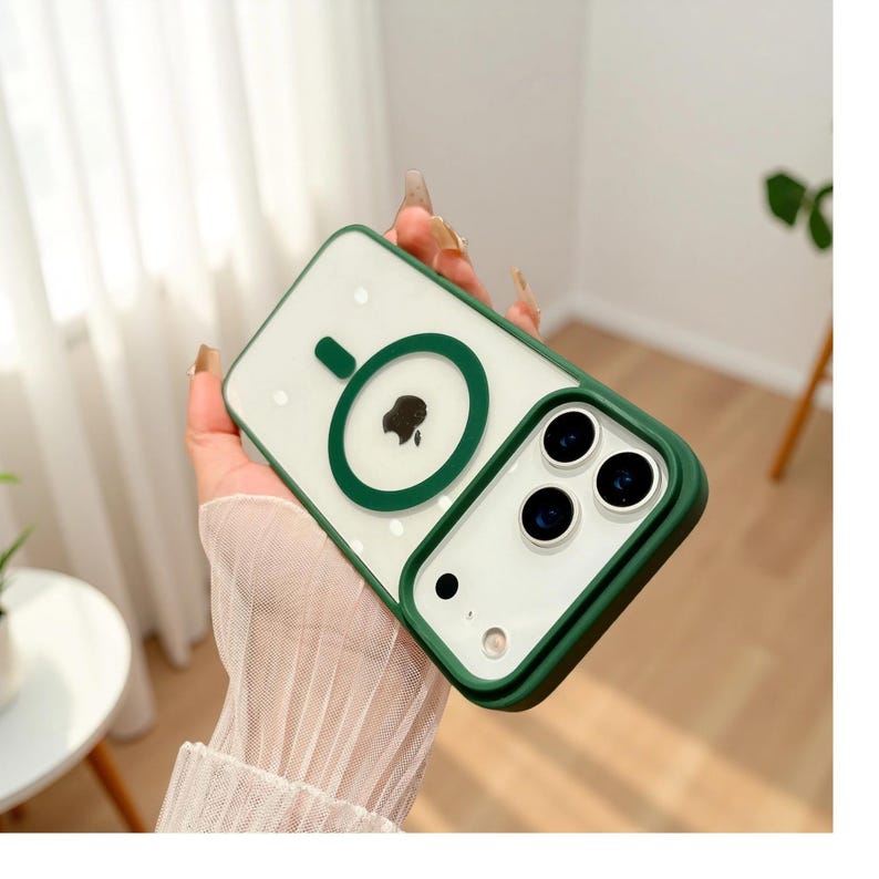 Puede incluir: Una funda transparente para tel&eacute;fono con borde y detalles verdes. La funda presenta un c&iacute;rculo verde con el logotipo de una manzana negra y un recorte para la c&aacute;mara. La funda est&aacute; dise&ntilde;ada para proteger el tel&eacute;fono de ara&ntilde;azos y da&ntilde;os.